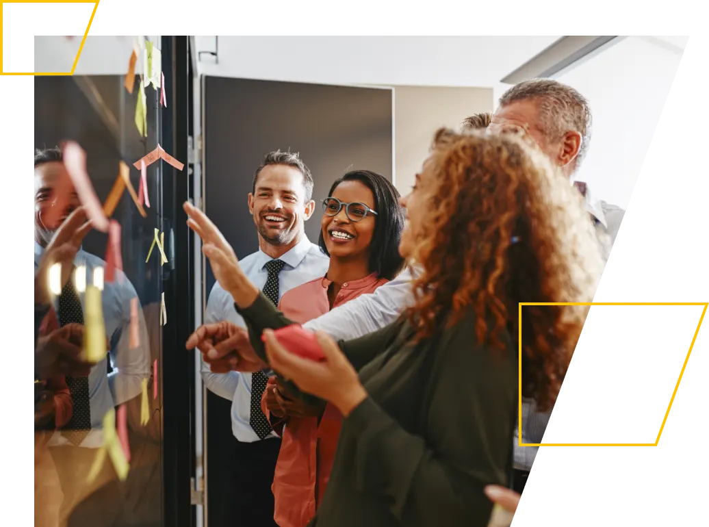 Group of smiling businesspeople laughing while brainstorming on a whiteboard